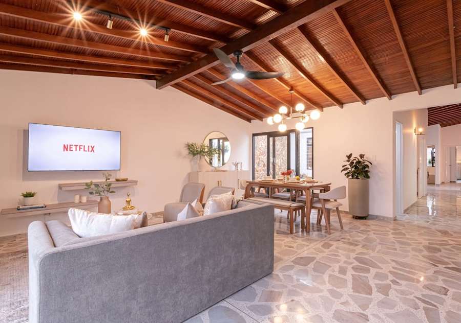 Wide view of the living room with sofa, smart TV and dining area