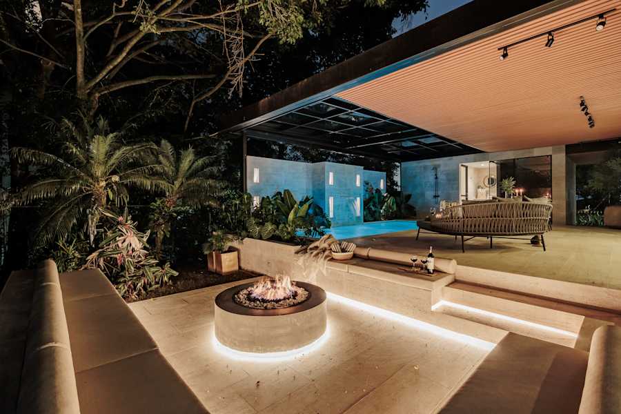 Outdoor fire lounge by the heated pool, warmly lit at night