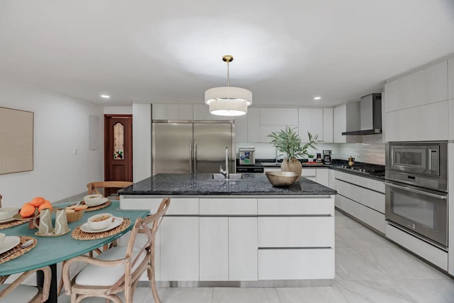 Fully equipped kitchen designed for group stays and private chef service, with a granite island, French door refrigerator, icemaker, dishwasher, premium oven, coffee station, and breakfast table