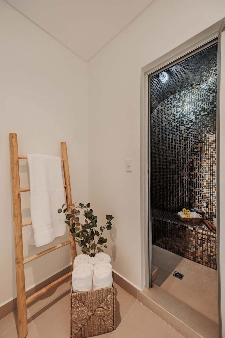 Primary Suite – Private Steam Room: Private hammam inside the master suite bathroom, featuring warm lighting, mosaic tiles, bench, and fresh towels—designed for relaxation, privacy, and luxury.